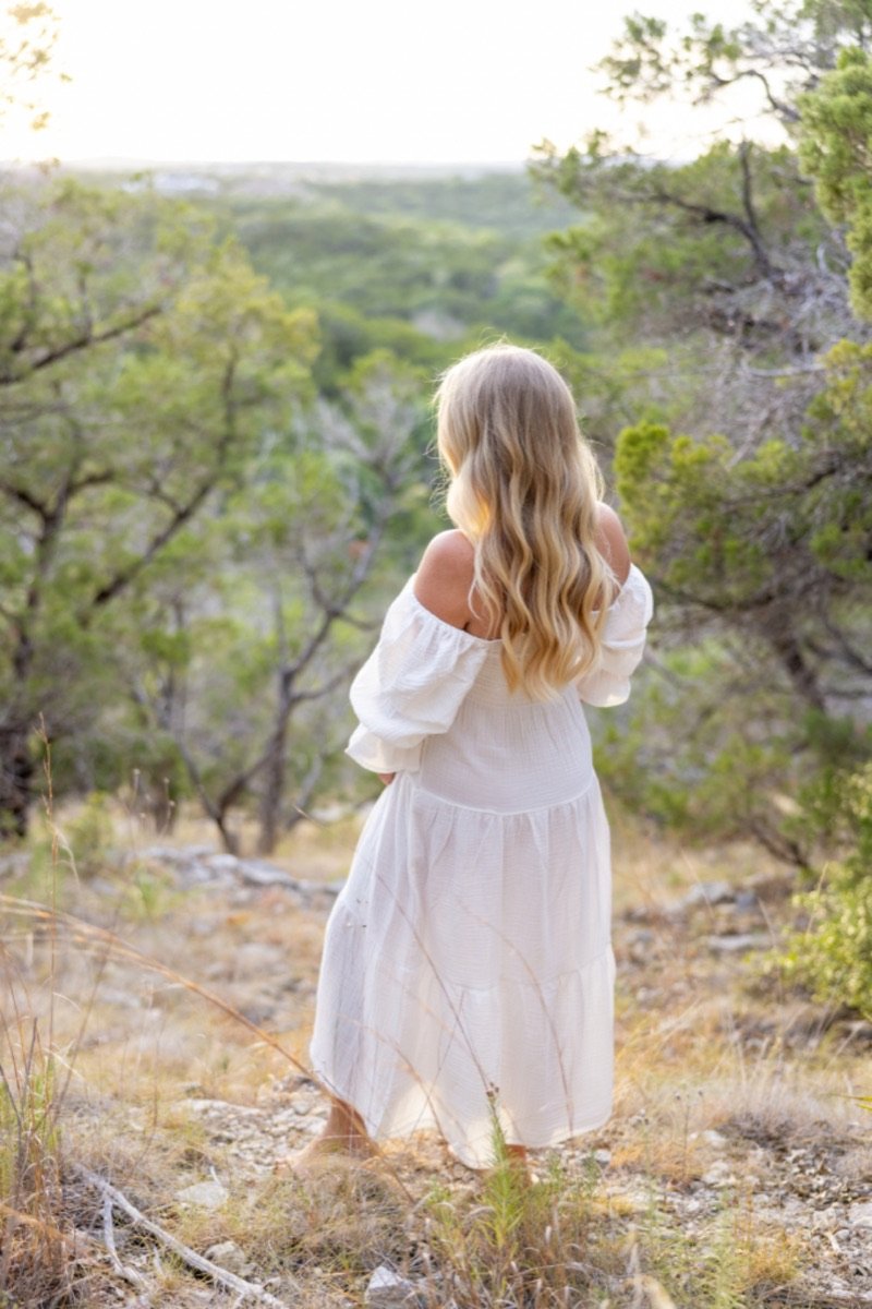 Mujer de espaldas con vestido blanco en el bosque