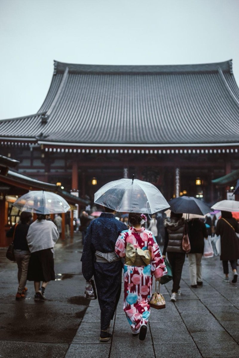 Templo japonés con visitantes bajo paraguas