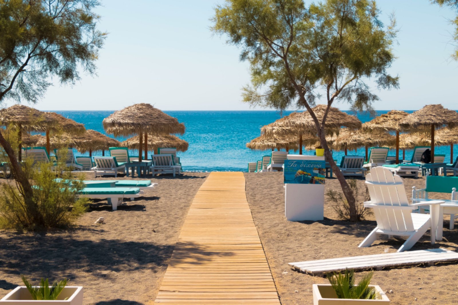 Playa griega con sombrillas de paja y mar turquesa